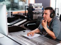 Hispanic sound engineer working at mixing panel in the recording studio
